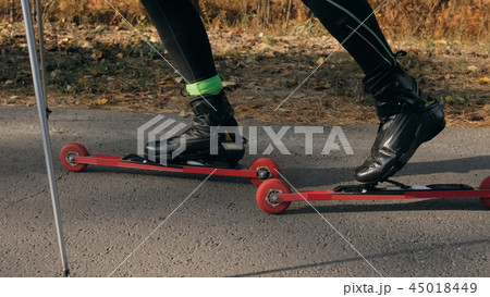 Training an athlete on the roller skaters. Biathlon ride on the roller skis with ski poles, in the Training an athlete on the roller skaters. Biathlon ride on the roller skis with ski poles, in the 45018449