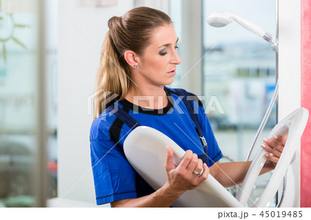 Female maintenance worker checking the quality of a toilet seat  45019485