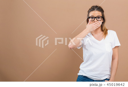 Young woman covering her mouth Young woman covering her mouth 45019642
