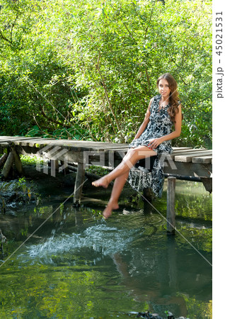 Pretty girl sits on wooden bridge Pretty girl sits on wooden bridge 45021531