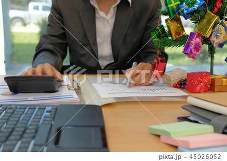 financial adviser use calculator to calculate revenue & budget. accountant doing accounting during christmas holiday financial adviser use calculator to calculate revenue & budget. accountant doing accounting during christmas holiday 45026052