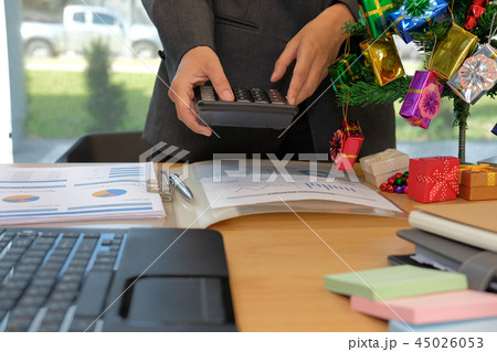 financial adviser use calculator to calculate revenue & budget. accountant doing accounting during christmas holiday financial adviser use calculator to calculate revenue & budget. accountant doing accounting during christmas holiday 45026053