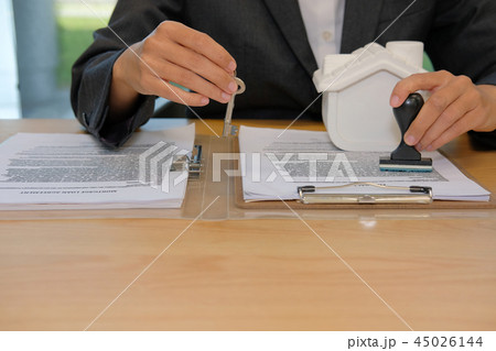 real estate agent with house key stamping approved on mortgage loan contract agreement document 45026144