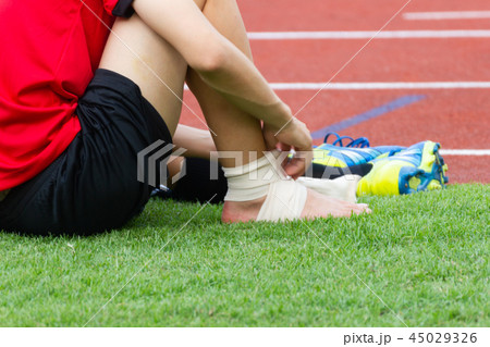 man applying compression bandage onto ankle injury 45029326