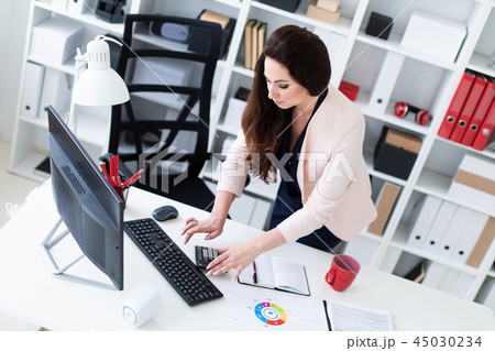 Young girl standing near the computer Desk and typing on the keyboard. 45030234
