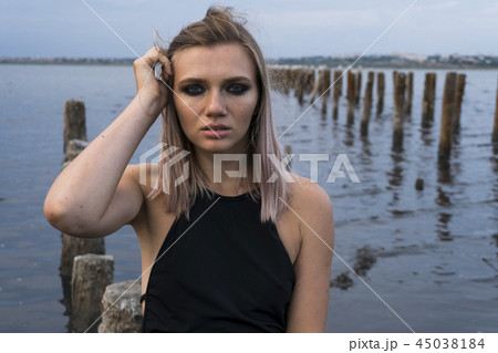 Portrait of Blonde Caucasian Girl in a Healthy Black Mud in old Firth with Wooden Posts for Salt 45038184