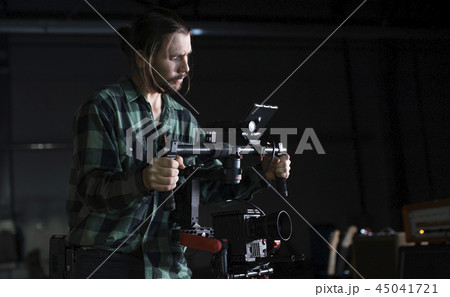 Professional videographer holding camera on 3-axis gimbal. Videographer using steadicam. Pro Professional videographer holding camera on 3-axis gimbal. Videographer using steadicam. Pro 45041721