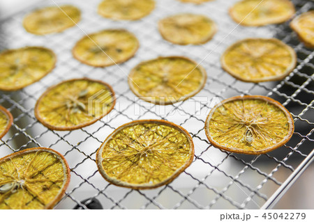 Candied orange slices on grid for drying. Dried fruits which can be used as a decoration to the meal Candied orange slices on grid for drying. Dried fruits which can be used as a decoration to the meal 45042279