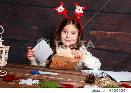 Child writes letter to Santa Claus . Funny girl in Santa hat writes letter to Santa 45046044