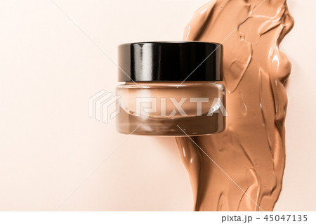 A glass jar of foundation for a face with a sample of the product itself. 45047135
