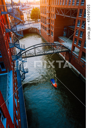 Small Boat under bridge over canal between red brick buildings in the old warehouse district 45049505