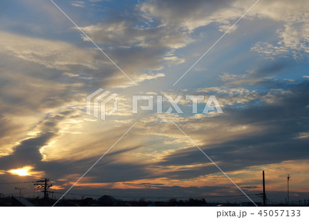 青く輝く神々しい幻想的な夕焼け空に映える雲と地平線の写真素材