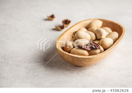Pecan nuts in a wooden bowl on a white background. Pecan nuts in a wooden bowl on a white background. 45062626
