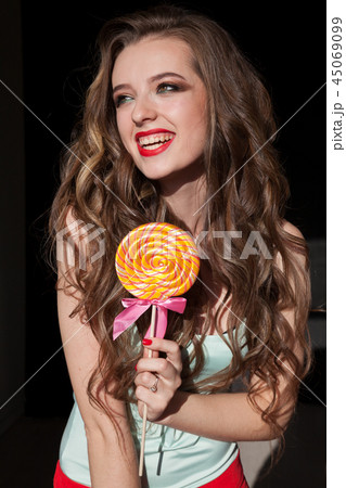 Portrait of a cheerful girl with a sweet candy colorful lollipop 45069099