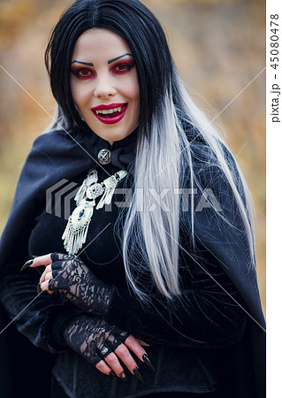 Photo of smiling vampire girl in black cloak with amulet 45080478