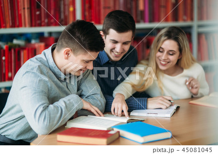University students sitting together at the table with books and laptop. Happy young people doing University students sitting together at the table with books and laptop. Happy young people doing 45081045