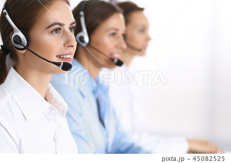 Group of callcenter operators at work. Focus at beautiful business woman in headset Group of callcenter operators at work. Focus at beautiful business woman in headset 45082525