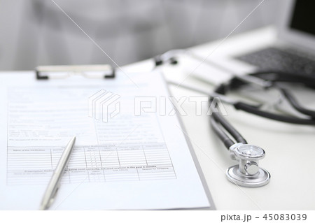 Stethoscope, clipboard with medical form lying on hospital reception desk with laptop computer 45083039