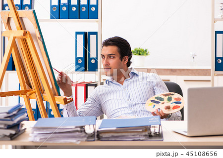 Young handsome employee enjoying painting at the office Young handsome employee enjoying painting at the office 45108656