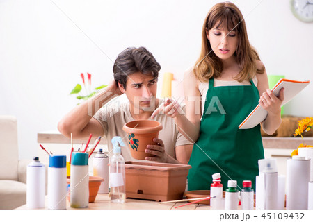 Couple decorating pots in workshop during class Couple decorating pots in workshop during class 45109432