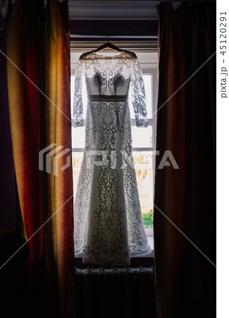 Wedding dress hanging on the window in the room 45120291