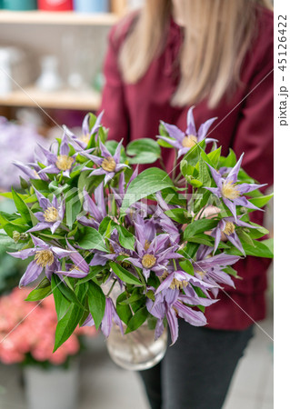 bouquet of lilac clematis flowers in glass vase. the work of the florist at a flower shop. A glass 45126422