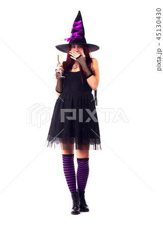 Full-length photo of surprised witch with wine glass with wine in black dress, striped socks Full-length photo of surprised witch with wine glass with wine in black dress, striped socks 45130430