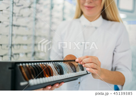 Optician holds box with lenses of different colors Optician holds box with lenses of different colors 45139385