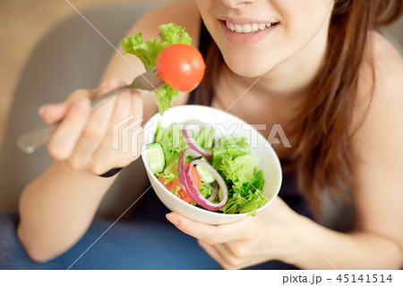 close-up young caucasian woman eating fresh vegetable salad close-up young caucasian woman eating fresh vegetable salad 45141514