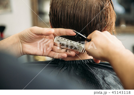 Master cuts hair and beard of men in the barbershop, hairdresser makes hairstyle for a young man Master cuts hair and beard of men in the barbershop, hairdresser makes hairstyle for a young man 45143118