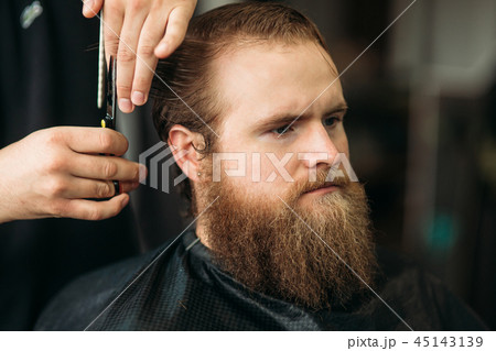Barber using scissors and comb in barbershop Barber using scissors and comb in barbershop 45143139