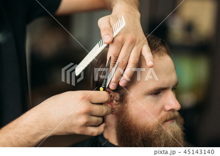 Barber using scissors and comb in barbershop 45143140