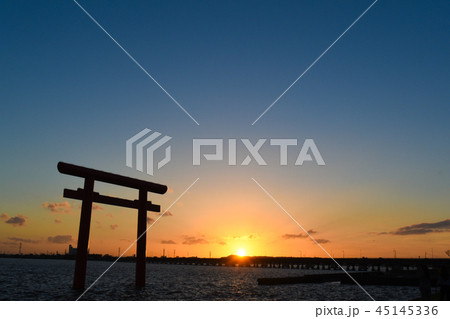 水面に浮かぶ鳥居と水平線に夕日 45145336