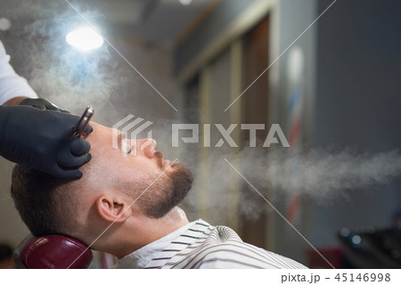 Side view of relaxed man getting haircut in barber shop 45146998
