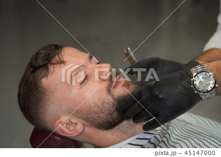 Closeup of male client during shaving in barber shop 45147000