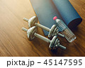Pair of dumbbells with blue yoga mat on wood floor 45147595