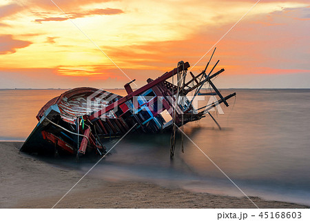 Shipwreck or wrecked boat on beach in the sunset.  45168603