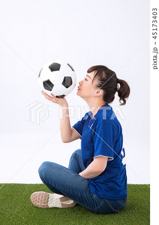 サッカーボールにキスする女性 笑顔 の写真素材