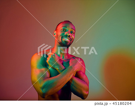 Close up portrait of a young naked african man looking at camera indoors Close up portrait of a young naked african man looking at camera indoors 45180204