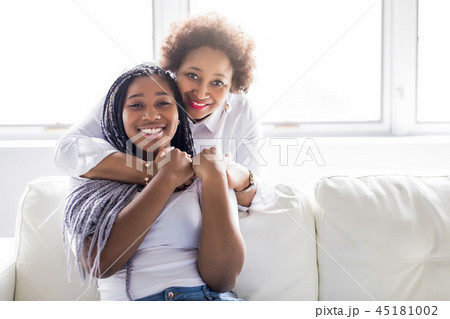 affectionate mother and daughter sitting on sofa 45181002