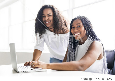 Two teen at desk in her office with laptop Two teen at desk in her office with laptop 45181325
