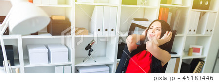 Beautiful young girl in headphones sits in the office at the table. Beautiful young girl in headphones sits in the office at the table. 45183446