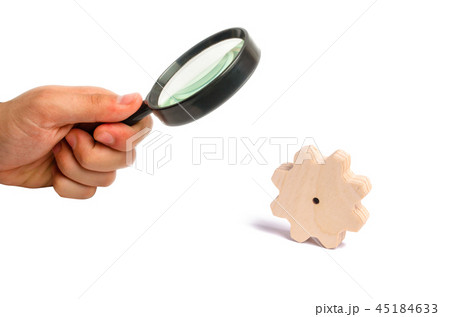 Magnifying glass is looking at the Wooden gear Magnifying glass is looking at the Wooden gear 45184633
