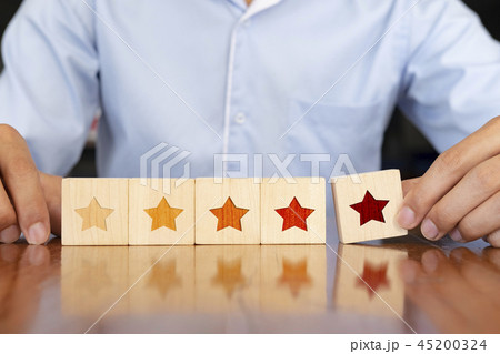 Businessman putting wooden five star shape. 45200324