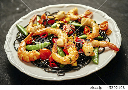 fresh, delicious black spaghetti with grilled shrimps, tomatoes, chilli, on a white plate 45202108