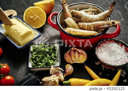 fresh delicious raw tiger prawns in a pot with parsley, lemon, butter, tomatoes and chili peppers fresh delicious raw tiger prawns in a pot with parsley, lemon, butter, tomatoes and chili peppers 45202125