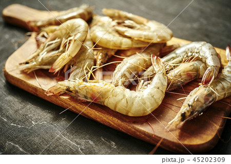 fresh delicious raw tiger prawns on a wooden board on a black table 45202309