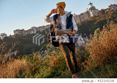 Young tourist blogger is exploring the map and talking on the smart phone 45214218