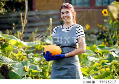 Image of smiling woman with pumpkin in hands at garden Image of smiling woman with pumpkin in hands at garden 45216217