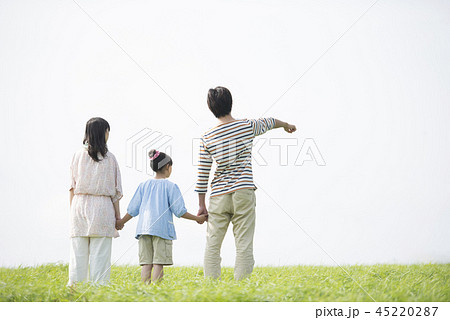 草原で手をつなぐ家族の後姿の写真素材